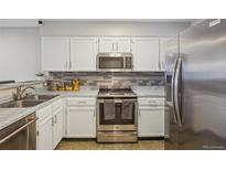 Updated kitchen featuring stainless steel appliances, tiled backsplash, and bright white cabinetry at 1818 S Quebec Way # 11-3, Denver, CO 80231