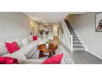 Open-concept living room with hardwood floors, couch, stairs and view into the kitchen at 1818 S Quebec Way # 11-3, Denver, CO 80231