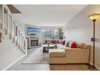 Spacious living room with a brick fireplace, large sofa, and stairs to the upper level at 1818 S Quebec Way # 11-3, Denver, CO 80231