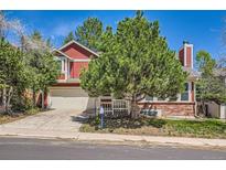 Charming two-story home boasts a well-manicured lawn, mature trees, and a classic red and brick exterior at 17509 E Kenyon Dr, Aurora, CO 80013