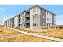 Modern apartment complex with stone accents, gray siding, and well-maintained landscaping at 16841 Askins Loop # 101, Parker, CO 80134