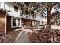 Charming townhome featuring a brick facade, white siding, and mature trees in a well-maintained community at 10330 E Jewell Ave # 67, Aurora, CO 80247