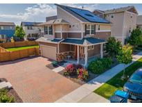 Beautiful two-story home featuring solar panels, a brick driveway, and colorful landscaping at 10071 Yampa Ct, Commerce City, CO 80022