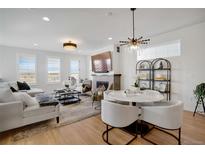 Bright and airy living room with a fireplace, plush seating, and open to the adjacent dining area at 14998 Cast Pebble Cir, Parker, CO 80134
