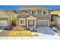 Charming home features stone accents, gray siding, a two-car garage, and manicured lawn at 885 Hearthstone Ave, Brighton, CO 80601