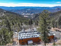 Breathtaking aerial view of a mountain home with solar panels and stunning views of the surrounding landscape at 11450 Marks Dr, Conifer, CO 80433