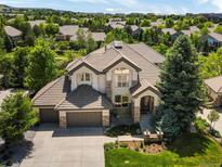 An attractive two-story home featuring a three-car garage, tile roof, and beautiful landscaping at 10057 S Shadow Hill Dr, Lone Tree, CO 80124