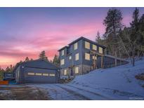 Beautiful mountain home featuring stone accents, multiple windows, and an adjacent garage under a vivid colorful sunset at 11932 Coal Creek Heights Dr, Golden, CO 80403