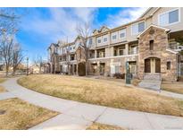 Tan townhouse building with stone accents, set against a blue sky at 1535 S Florence Way # 407, Aurora, CO 80247