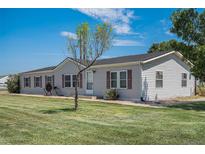 Charming single-story home featuring a well-maintained lawn and classic vinyl siding at 8260 County Road 39, Fort Lupton, CO 80621