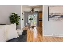 View of a light-filled dining area with hardwood floors and a glass table, next to the living room at 13483 Achilles Dr, Lone Tree, CO 80124