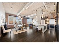 An open floor plan features a kitchen, dining and living area with exposed ceiling, brick accent wall and large windows at 1301 Wazee St # 3C, Denver, CO 80204