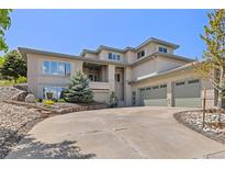 Spacious home featuring an attached three-car garage, elegant landscaping, and a welcoming front entrance at 6405 Eagle Feather Trl, Littleton, CO 80125
