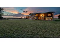 Expansive exterior view of home with large lawn and a colorful sunset in the background at 11881 County Road 37, Fort Lupton, CO 80621