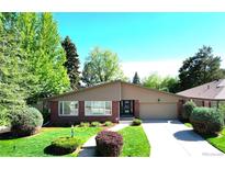 Charming single-story home with lush front yard and a brick facade and well-maintained landscaping at 6630 E Virginia Ave, Denver, CO 80224