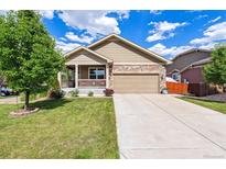 Charming home featuring stone accents, a covered porch, a well-manicured lawn, and an attached two-car garage at 10288 Olathe Way, Commerce City, CO 80022