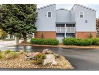 Charming building exterior featuring balconies, brick accents, lush landscaping, and assigned unit entrances at 7665 E Eastman Ave # 202A, Denver, CO 80231