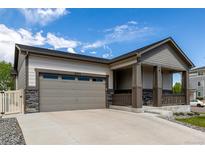 Charming home featuring a covered front porch with stone accents and an attached two-car garage at 10595 Boston St, Commerce City, CO 80640