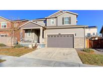 Charming two-story home featuring a gray exterior, well-maintained lawn, and inviting front porch at 9448 Richfield St, Commerce City, CO 80022