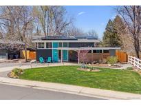 Charming home with a blue door, solar panels, a well-manicured lawn, and mature trees at 1325 S Ivy Way, Denver, CO 80224