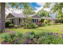 Charming home featuring a well-manicured front yard with colorful flower beds and mature trees at 860 Magnolia St, Denver, CO 80220