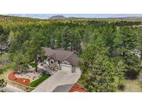 Stunning aerial view of home, showcasing lush surroundings and mountain backdrop at 1151 Kenosha Dr, Larkspur, CO 80118
