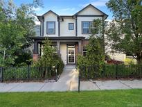 Charming two-story home with a landscaped yard, black iron fence, and inviting front porch at 8056 E 35Th Ave, Denver, CO 80238