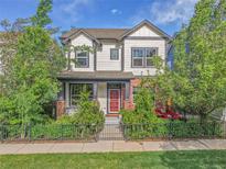 Charming two-story home featuring a landscaped yard, iron fence, and inviting red front door at 8056 E 35Th Ave, Denver, CO 80238