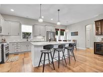 Bright kitchen with stainless steel appliances, white cabinets, quartz countertops, and an island with barstool seating at 8056 E 35Th Ave, Denver, CO 80238