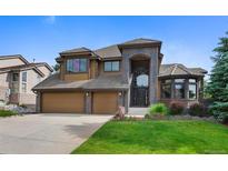 Inviting home featuring a grand entrance, three-car garage, and well-manicured lawn at 34 Amaranth Dr, Littleton, CO 80127