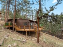Charming mountain home with a spacious wooden deck nestled amongst tall pine trees on a gently sloping hillside at 4786 Forest Hill Rd, Evergreen, CO 80439