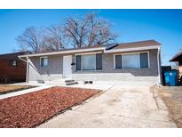 Charming grey brick home with a well-manicured yard on a sunny day at 6671 Oneida St, Commerce City, CO 80022