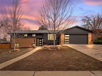 Charming home with brick and gray siding, a well-manicured lawn, and a two-car garage, enhanced by a colorful sunset backdrop at 2723 S Knoxville Way, Denver, CO 80227