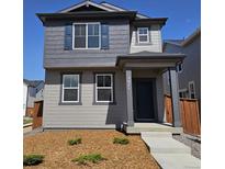 Charming two-story home with a covered porch, gray siding, and well-maintained landscaping at 2071 Generations Aly, Brighton, CO 80601