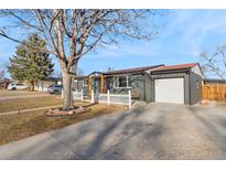 Charming single-story home with a well-maintained lawn, a white picket fence, and an attached garage at 5116 Jellison St, Arvada, CO 80002