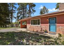 Inviting home exterior with a blue front door, stone accents, and lush landscaping at 9359 Barnes Ave, Conifer, CO 80433