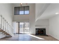 Bright living room with a fireplace, sliding glass door to a deck and light wood grain flooring at 4896 S Dudley St # 11, Littleton, CO 80123