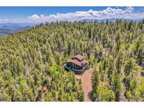 Stunning aerial view of a secluded home nestled in a dense forest with mountain views at 11333 Conifer Mountain Rd, Conifer, CO 80433