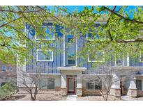 Inviting three-story home with blue siding, stone accents, and a red front door framed by budding trees at 9300 E Florida Ave # 1506, Denver, CO 80247