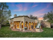 Inviting back patio with stone flooring, pillars, fire pit, and staircase to the second level at dusk at 1069 Crestmoor Dr, Boulder, CO 80303