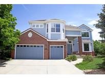 Charming two-story home with a well-manicured lawn, blue siding, red brick, and an attached two-car garage at 6254 S Riviera Ct, Aurora, CO 80016