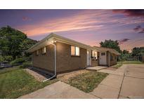 Charming brick home with a well-maintained lawn and beautiful landscaping at sunset at 1150 Rosemary St, Denver, CO 80220