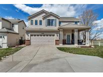 Charming two-story home with a well-manicured lawn, inviting front porch, and attached two-car garage at 19593 E Hollow Creek Dr, Parker, CO 80134