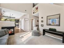 Inviting living room featuring high ceilings, a fireplace, and neutral decor at 19430 E 58Th Dr, Aurora, CO 80019