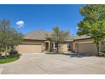 Charming home featuring a three-car garage, tan exterior, brick accents and mature landscaping at 6114 Salvia Ln, Arvada, CO 80403