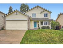 Charming two-story home with a well-manicured lawn, light yellow siding, and an attached two car garage at 4349 S Genoa Ct, Centennial, CO 80015