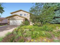 Two-story home featuring an attached garage and complemented by a vibrant and beautifully landscaped front yard at 13934 W Warren Dr, Lakewood, CO 80228