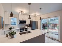 Bright kitchen features white cabinets, stainless appliances, large island, and access to the backyard at 1251 S Yosemite Way # 92, Denver, CO 80247