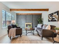 Cozy living room featuring a brick fireplace, wood beams, and modern furnishings at 1251 S Yosemite Way # 92, Denver, CO 80247