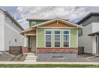 Charming two-story home with green siding, brick accents and white trim around large front windows at 959 Promenade Dr, Superior, CO 80027